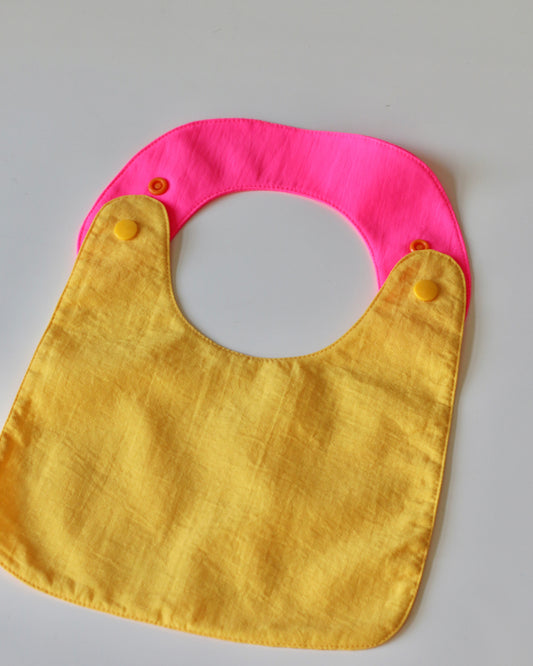 Babero reversible amarillo/fucsia