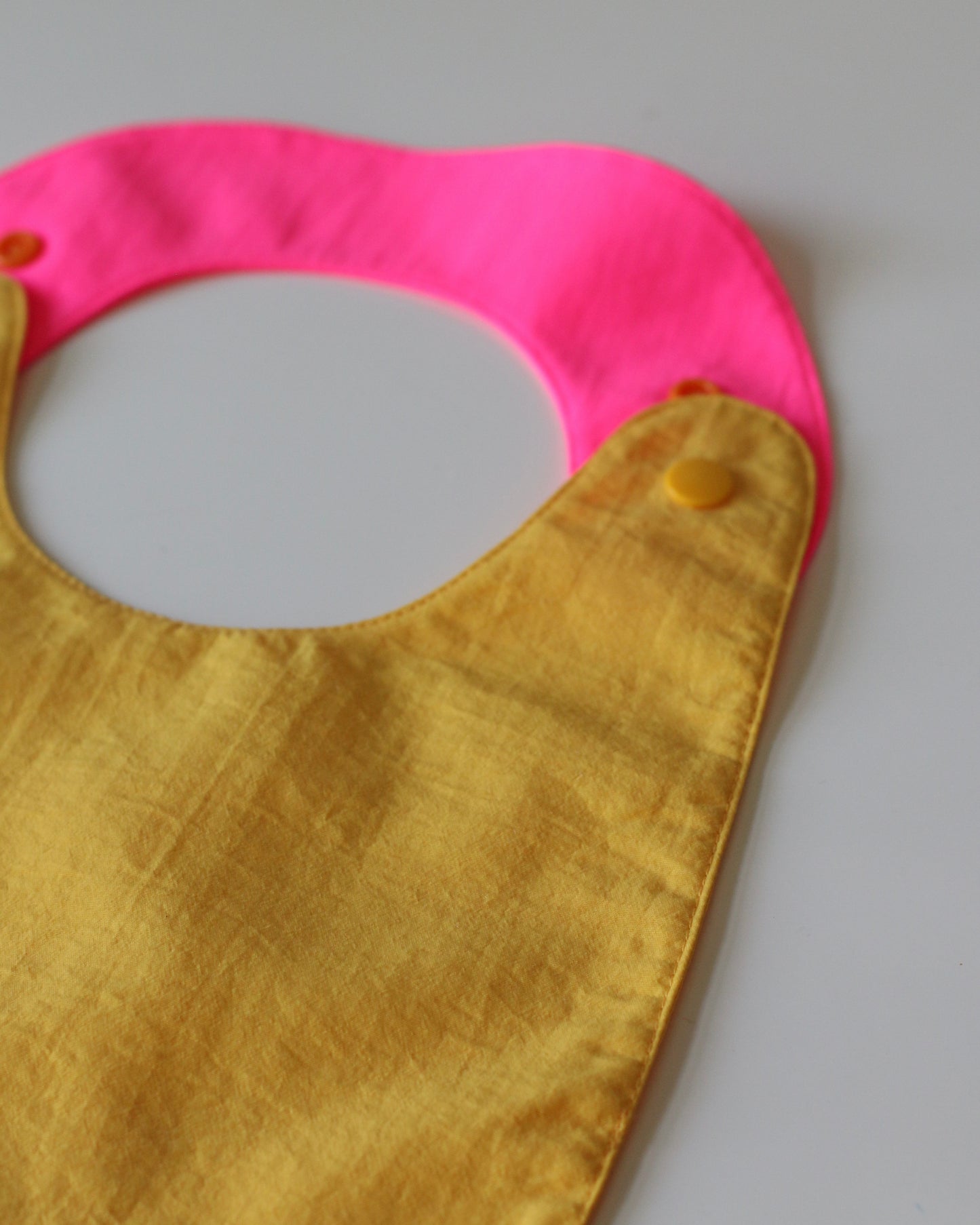 Babero reversible amarillo/fucsia