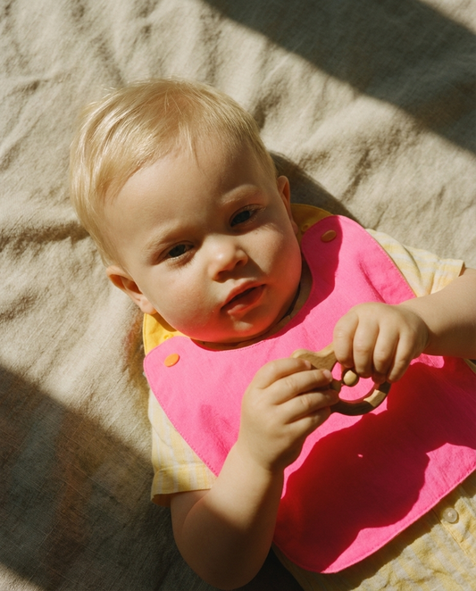 macadamia kids babero fucsia y amarillo