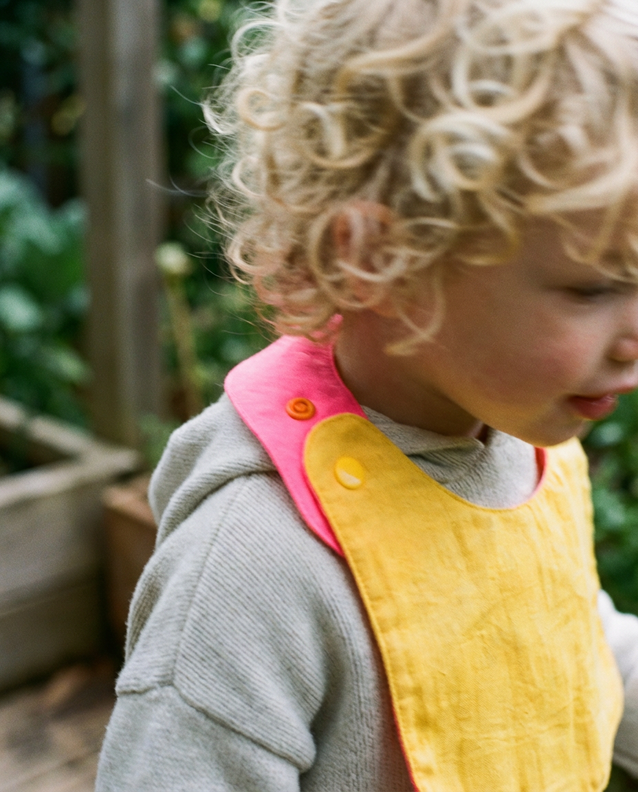 Babero reversible amarillo/fucsia