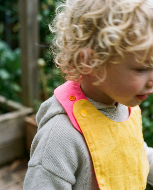 Babero reversible amarillo/fucsia